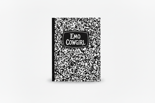 A black and white speckled composition notebook with a black spine and a black label on the cover that reads 'EMO COWGIRL' in white text, shown on a light gray background.