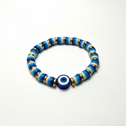 Handmade evil eye bracelet with blue disc beads and gold spacers on a bright white background
